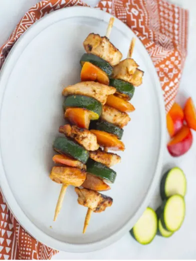 Chicken skewers on plate with peaches and zucchini