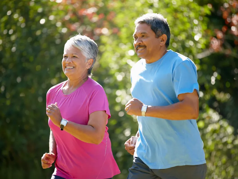Smiling senior Lation husband and wife outside jogging on a sunny day