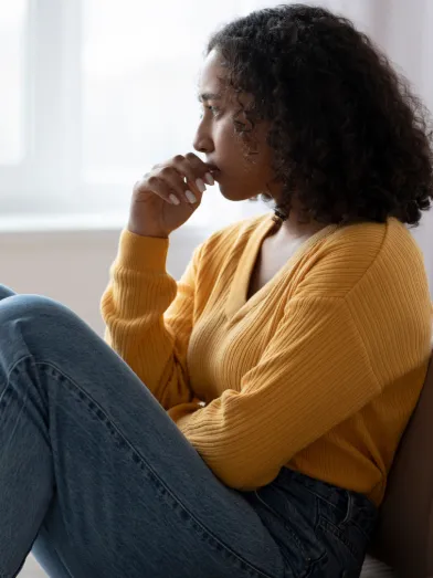 A woman looks sadly out of a window.