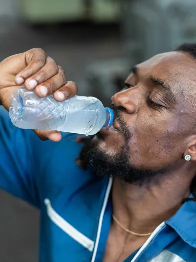 A thirsty man drinks a bottle of water to help with his high blood sugar