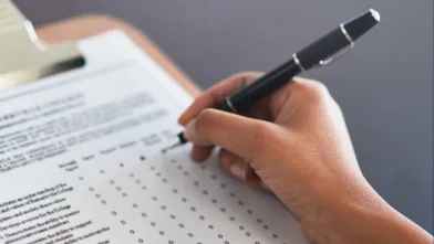 hand filling out a form on a clipboard